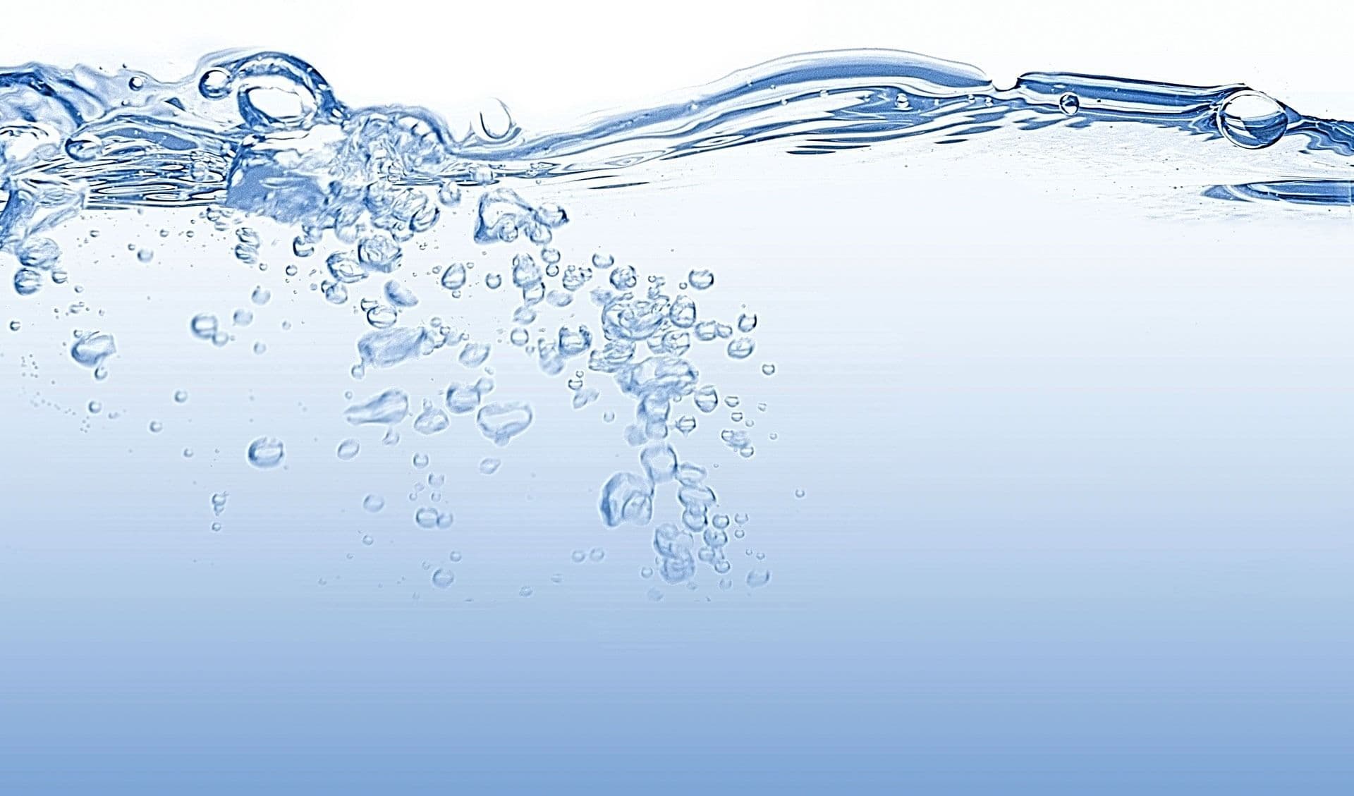 Clear water with bubbling movement against a gradient blue backdrop. The image conveys freshness and tranquility, capturing the fluidity of water.
